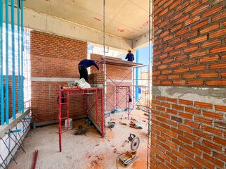 A bricklayer is laying bricks on a bathroom wall.