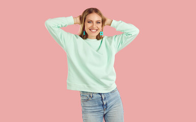 Happy, smiling young woman, dressed in light mint sweater and blue jeans, dances and throws her...