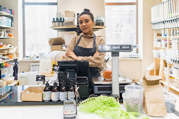 Portrait of confident African American woman owner of local zero waste grocery store wearing apron...