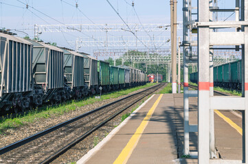 The railway platform at the station. A place for passengers to board the train. Railway tracks for railway transport. Freight cars at the station. Transportation of goods by rail.