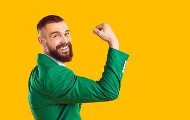 Happy man in suit shows his strong biceps muscles. Cheerful handsome fit bearded young guy in green...