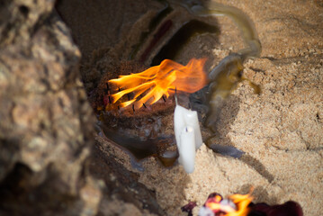 Candles burning among rocks on a beach to honor some religious entity.