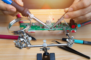 Technician is repairing motherboards and soldering equipment, repairing circuits.