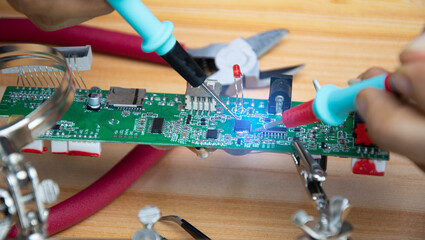 Technicians are repairing motherboards and checking electrical currents, repairing circuits.