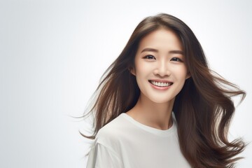 Naklejka premium Asian female, wearing a white t-shirt, beams with delight, proudly displaying her smile in a studio environment against a neutral white background. Generative AI.