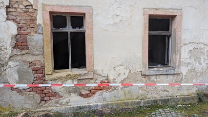 Fenster eines alten, maroden Hauses mit Absperrband