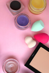 Various colorful beauty products on bright pink background. Top view.