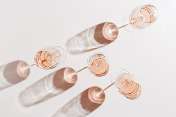 Rose wine glasses Minimal style above view. Holiday aesthetic still life photo, top view wineglass at natural light, sun shadows, beige pink pastel color, drink banner background, copyspace