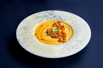 Pumpkin cream soup with chicken and croutons in a plate