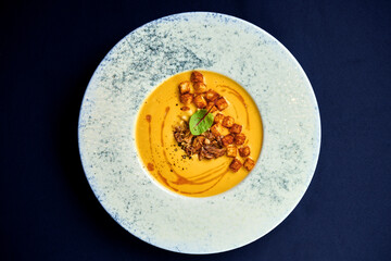 Pumpkin cream soup with chicken and croutons in a plate