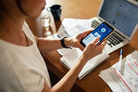 Close up woman checking bank account on smartphone at home
