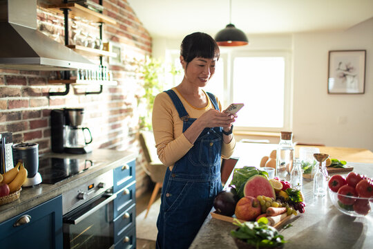 Woman taking picture of vegetables and fruits in the kitchen