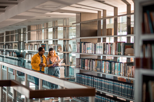 Female students reading in the college library together - Powered by Adobe