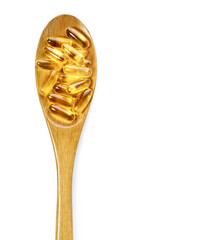 Omega 3 cod liver oil capsules in the wooden spoon on white background