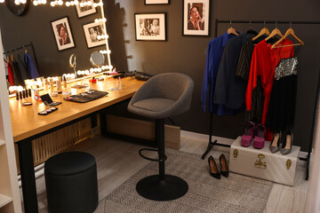 Chair, clothes rack and stylish mirror on dressing table in makeup room