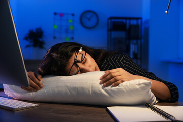 Tired overworked businesswoman napping with pillow at night in office