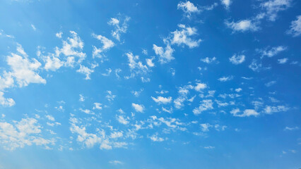 Clear blue sky with scattered fluffy white clouds on a sunny day, ideal for background or wallpaper