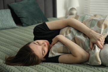 Sad young woman lying on bed at home