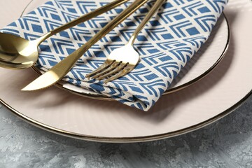 Clean plates, cutlery and napkin on light grey textured table, closeup