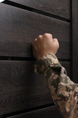 Military commissariat representative knocking on wooden door, closeup