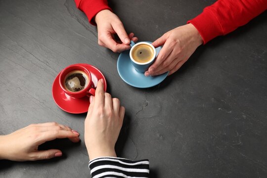 Women having coffee break at dark textured table, above view