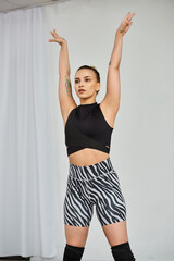 A graceful dancer in a striking outfit performs a dynamic choreography, while raising her hands
