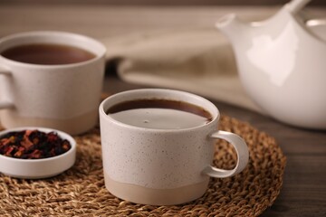 Aromatic tea and dry flower petals on wooden table, closeup