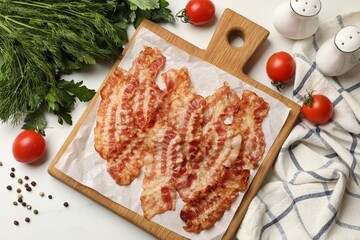 Delicious fried bacon slices and other products on white marble table, flat lay