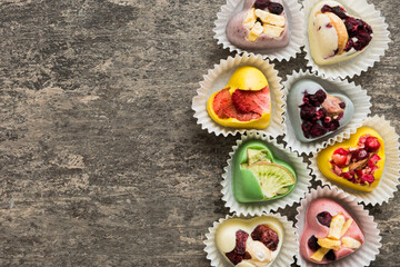 chocolate sweets in the form of a heart with fruits and nuts on a colored background. top view with space for text, holiday concept