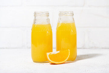 freshly squeezed orange juice in glass bottles on white table