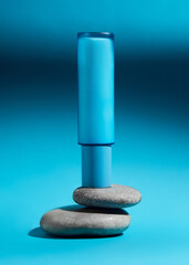 a blue bottle of cream stands on gray stones
