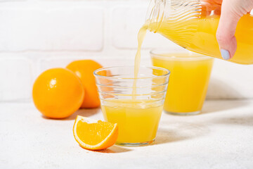 man pouring freshly squeezed orange juice into a glass