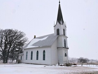 Fototapeta na wymiar An old country church on a relaxing winter day during a snow fall