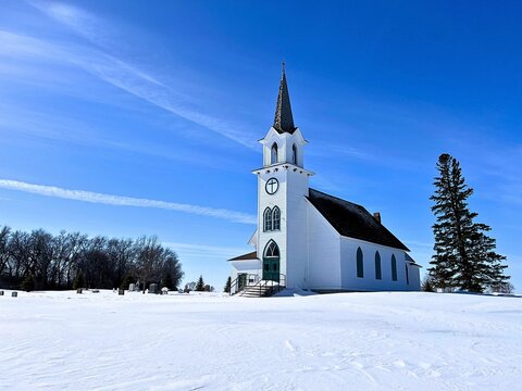 An adorable little country church standing tall on the snow covered prairie
