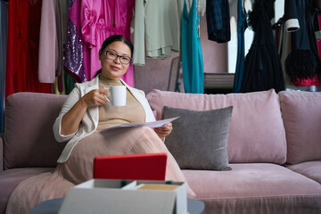 Obraz premium Beautiful lady with a cup of coffee sits on sofa