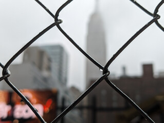 Image of a fence with the New York skyline in the backdrop.