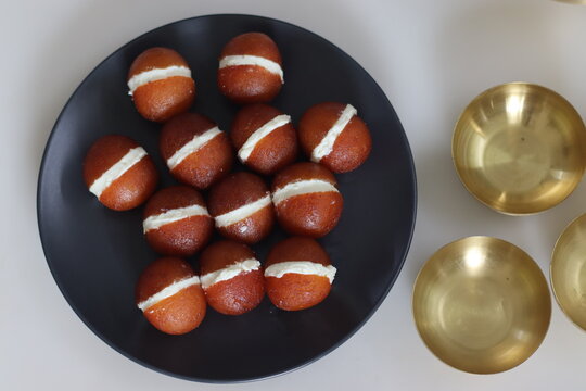 Malai Gulab Jamun. Gulab Jamun sandwich with milk cream filling. Fusion of Indian sweet dessert, golden brown, soft, and soaked in sugar syrup