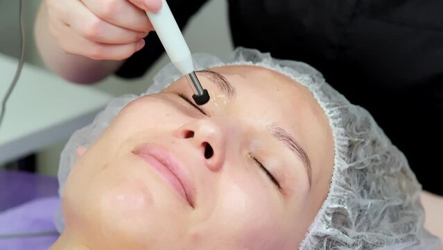 Hardware procedure in cosmetology. Close-up. Non-surgical facial skin lifting in a beauty clinic. A cosmetologist, a cosmetologist, moves a manipulator over the face. microcurrent treatment.