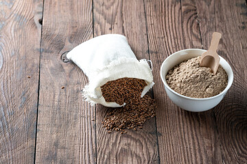 Flax seeds in a canvas bag and flaxseed flour in a bowl. Background with gluten-free alternative...