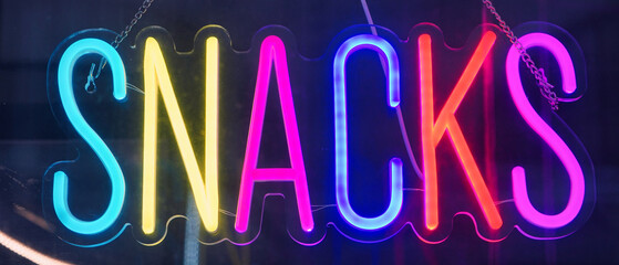 Neon sign in the form of a word SNACKS.