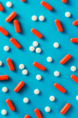 Orange capsule pills and white pills on blue background
