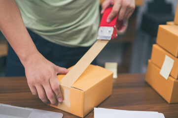 Hands of businessman sealing packages with tape at desk