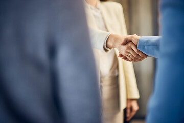 Focus on the two business females, shaking hands after the meeting.