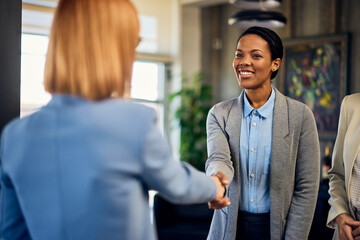 An African businesswoman meeting a new client, shaking hands, in the meeting room.