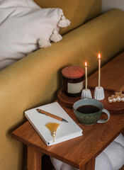 Coffee break - a cup of coffee, a diary, lighted candles on a wooden bench near the armchair