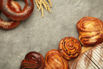 Bakery - various kinds of breadstuff. Bread rolls, bagel, sweet bun on grey concrete background.
