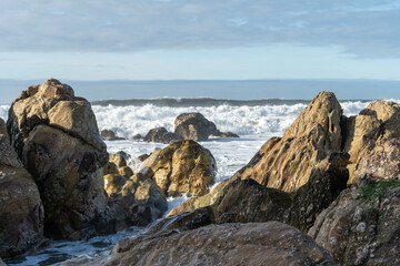 Rocks on the beach and sea waves on a sunny day in Porto, Portugal.