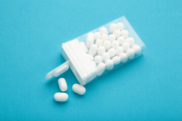 Tasty mint dragee candies with box on blue background.