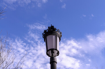 Fototapeta na wymiar plastic black street lamp on a background of blue sky with clouds