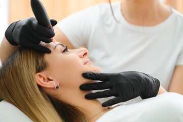 Process of creating permanent brow makeup with a machine at beauty salon